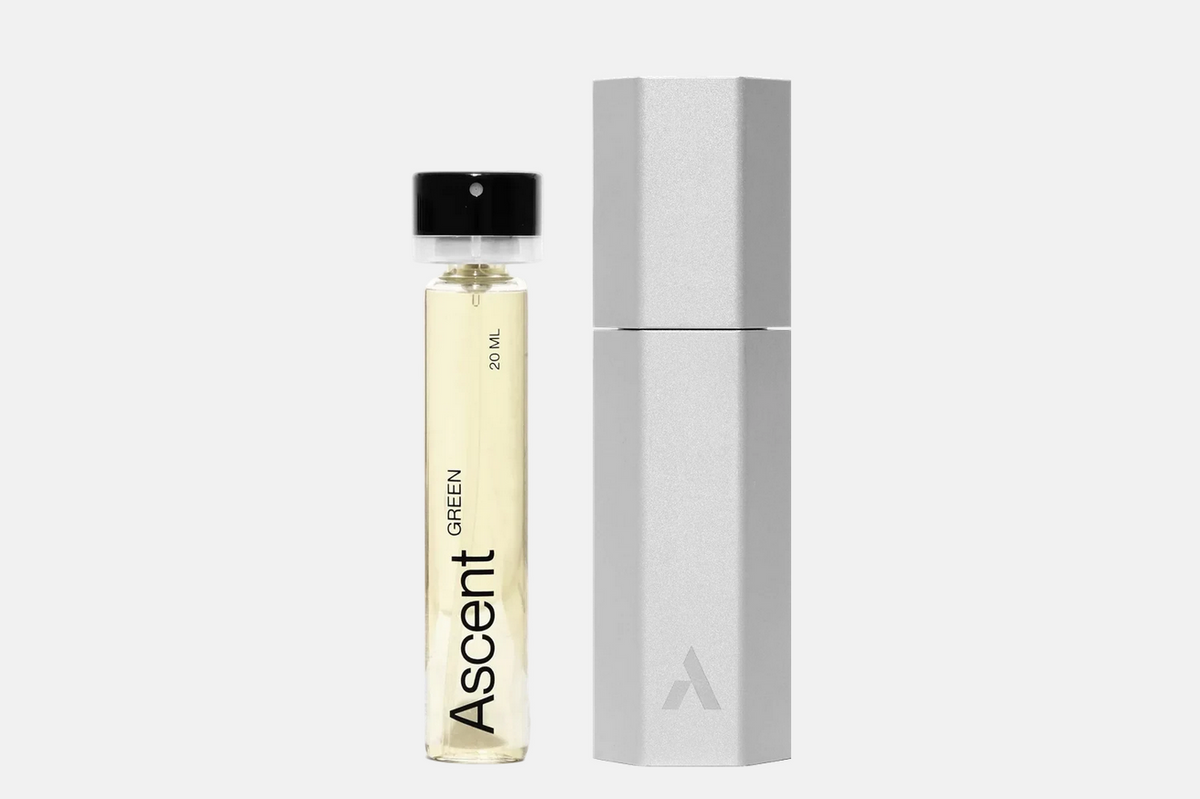 An Ascent Starter Pack - Green, featuring a clear glass vial of green perfume extract with a black cap standing next to a hexagonal metallic refillable travel case.