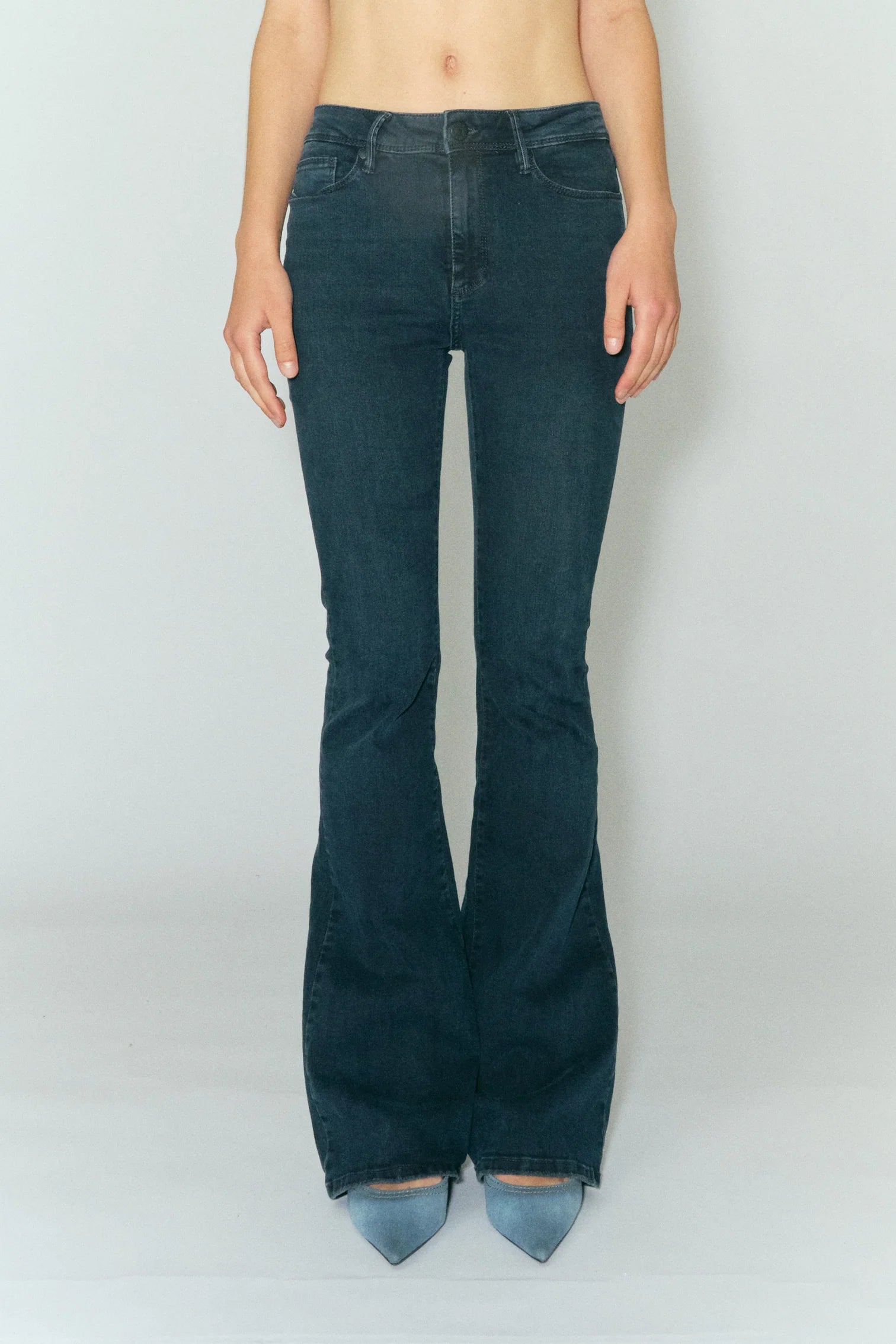 Model wears long flared jeans in dark blue wash