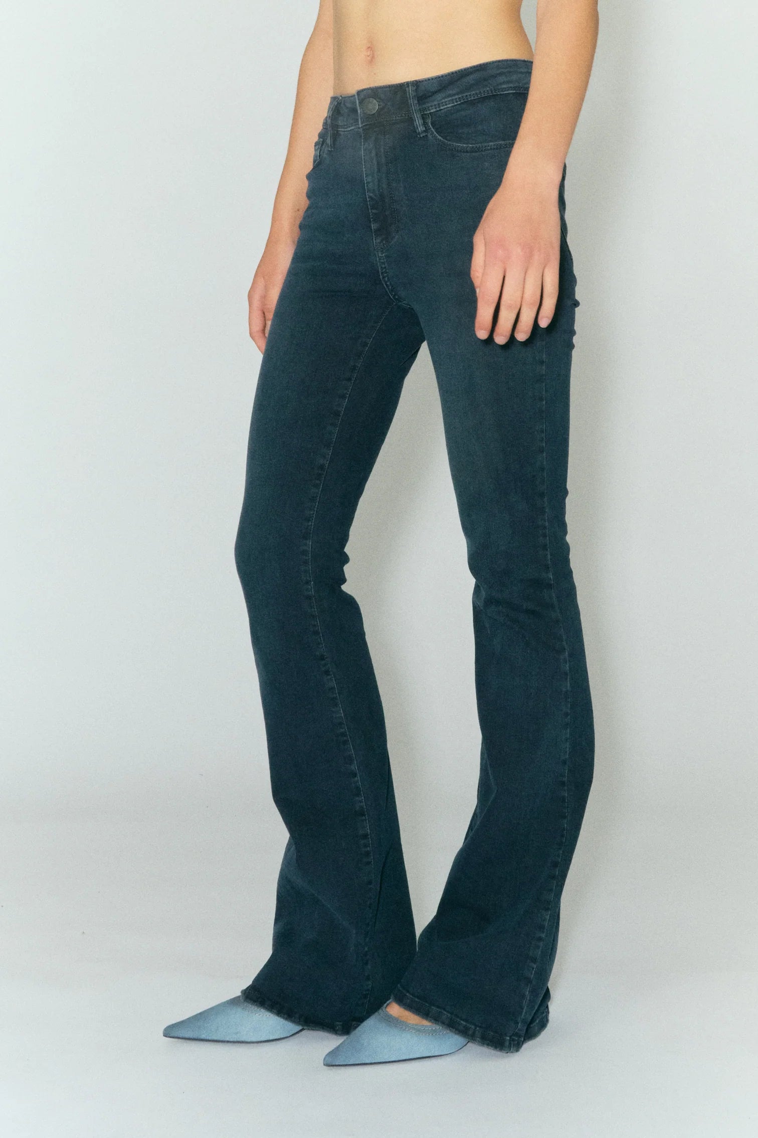 Model wears long flared jeans in dark blue wash
