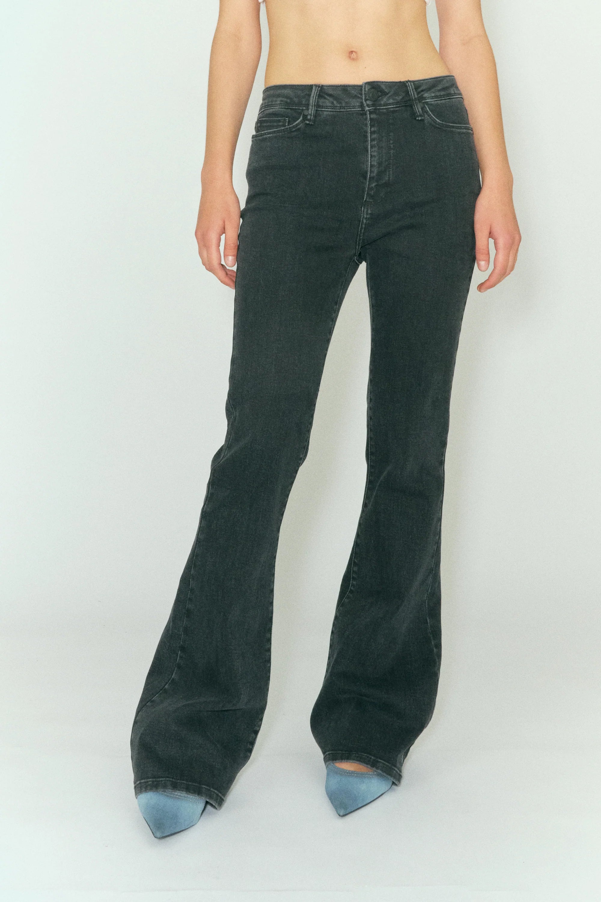 A woman in Tomorrow Denim's Albert Flare - Original Black high waist jeans with a flared hem posing for a photo.