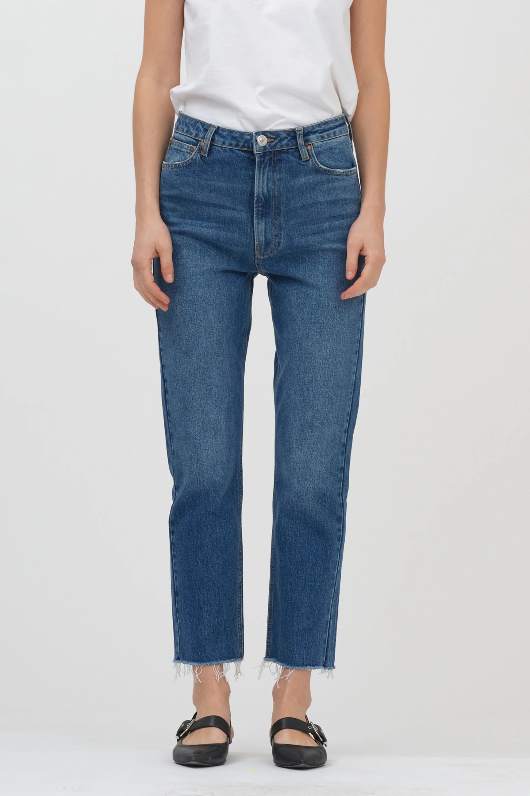 A woman wearing high-waisted Tomorrow Denim Anne Slim Jeans - Boston, made of organic cotton, paired with a white t-shirt.