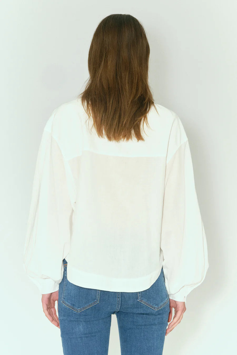 The back view of a woman wearing Tomorrow Denim's Sienna Supersized Shirt - Ecru and a white blouse made from organic cotton.