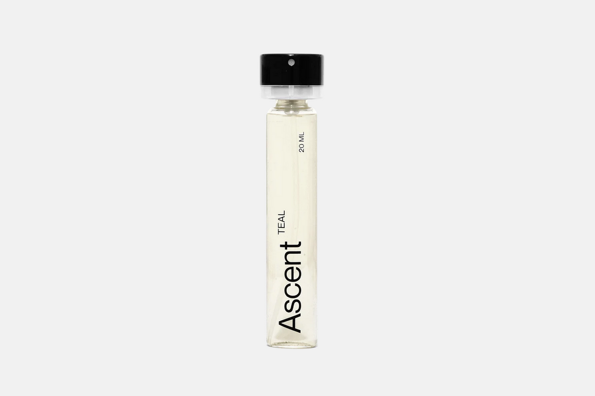 A cylindrical glass Ascent Refillable - Teal spray bottle with a black cap, labeled “Ascent” and “20 ml.”