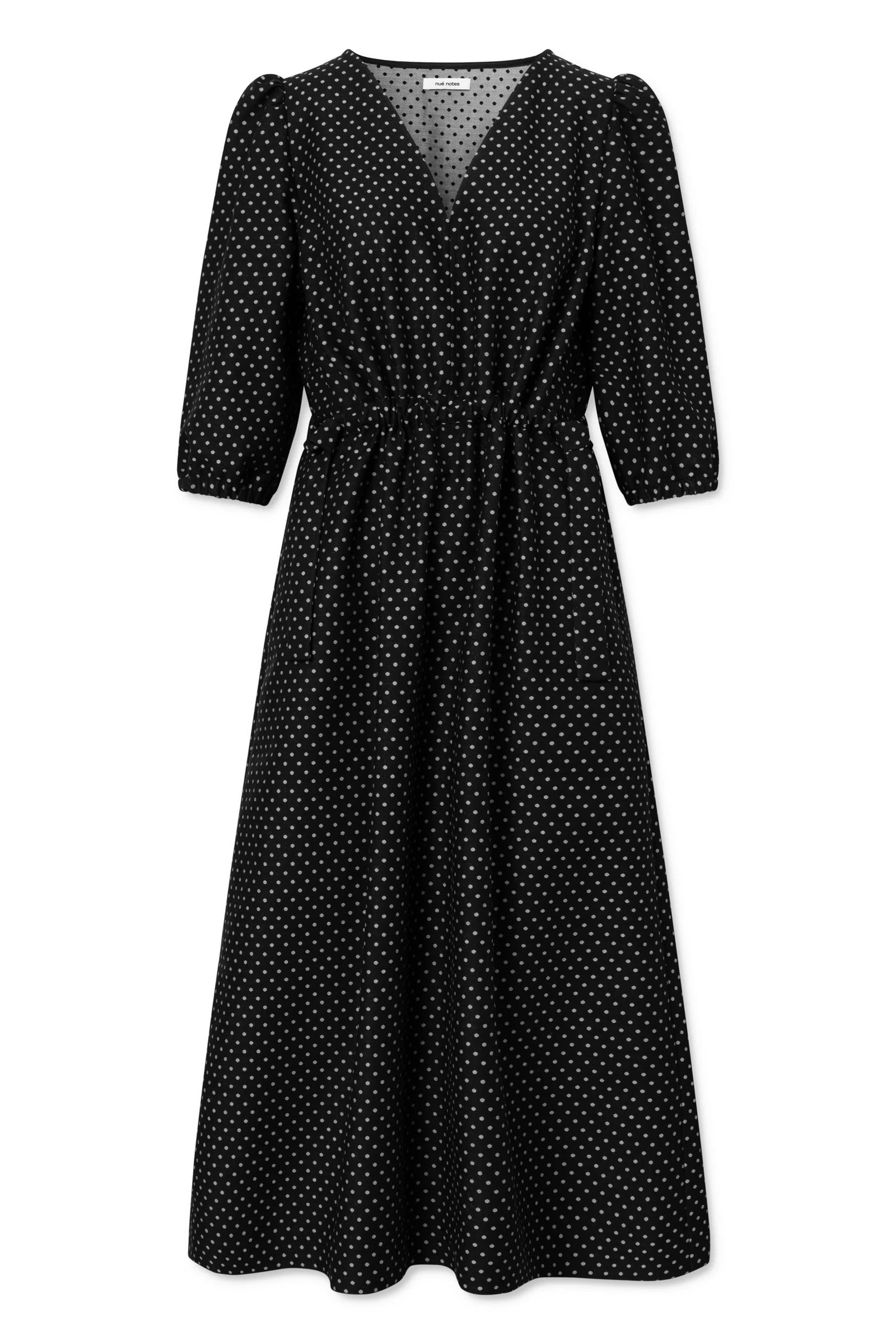 The Vilnius Dress - Black Polkadot by Nué Notes is a black midi dress with white polka dots, elbow-length puff sleeves, a V-neckline, a cinched waist, and an elegant A-line silhouette.