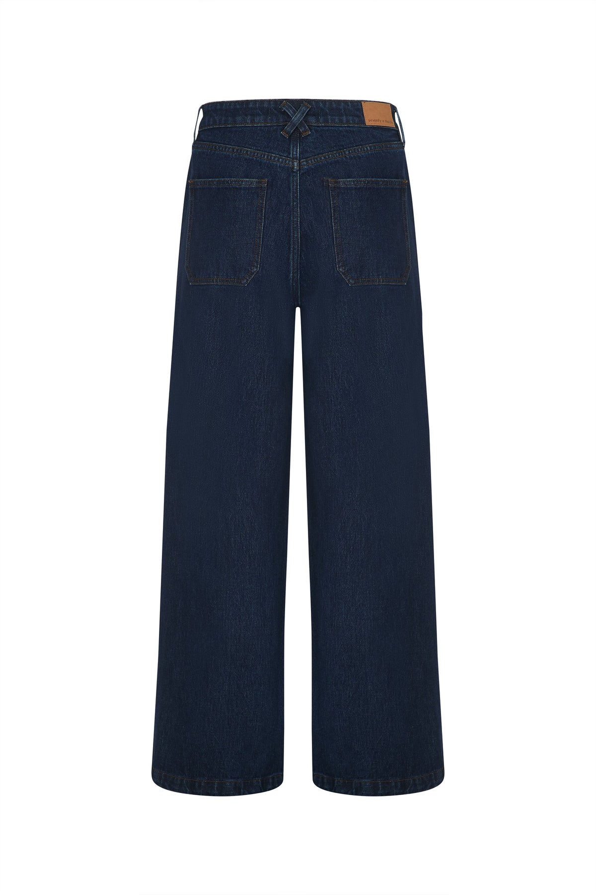 Back view of Seventy & Mochi’s Bay jean in Americana, a dark blue super high rise style with an extra-wide leg silhouette. Features include two rear pockets, a tan leather patch on the waistband, and rigid denim for a structured finish.