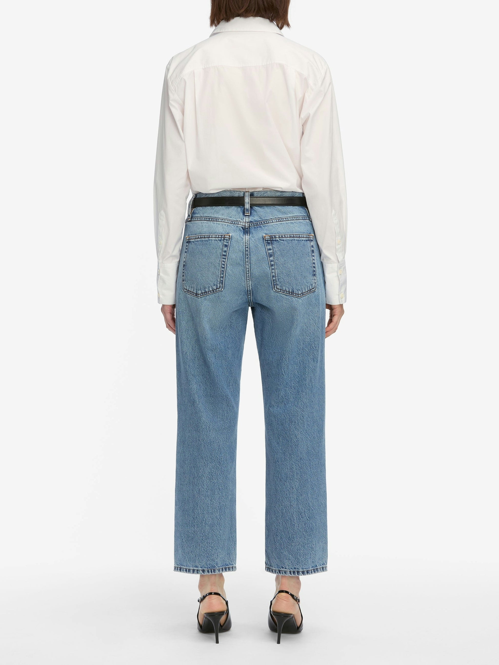 Person wearing light blue jeans and a white shirt on a white background