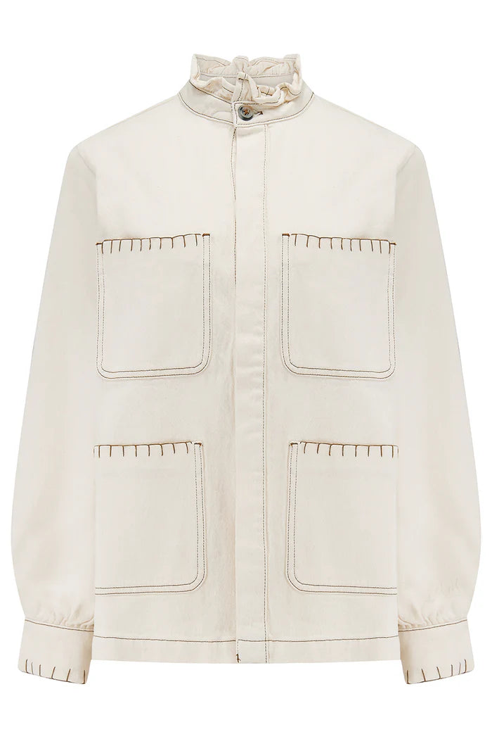 The Pablo Denim Jacket - Ecru by Seventy & Mochi features a stand collar, front button closure, two large front pockets, and visible beige stitching along pockets and edges.