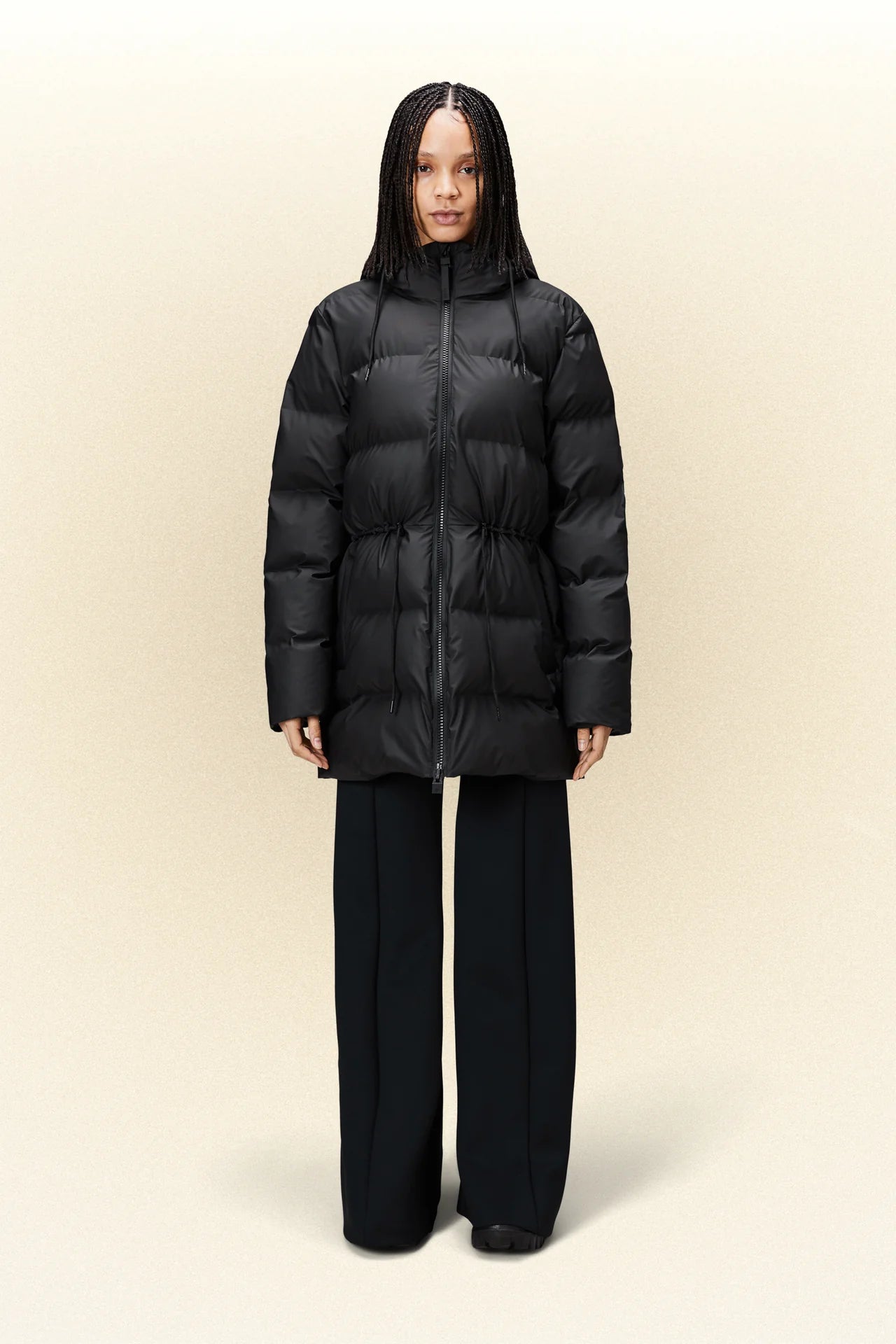 A woman wearing the Rains W Alta Puffer Parka - Black and wide leg pants.