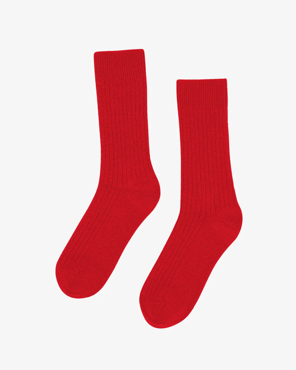A pair of Colorful Standard Merino Wool Blend Socks in plain red, featuring a ribbed crew design, is laid flat on a white background.