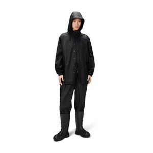 person wears all black clothing with the rains waterprrof fishtail jacket in black 