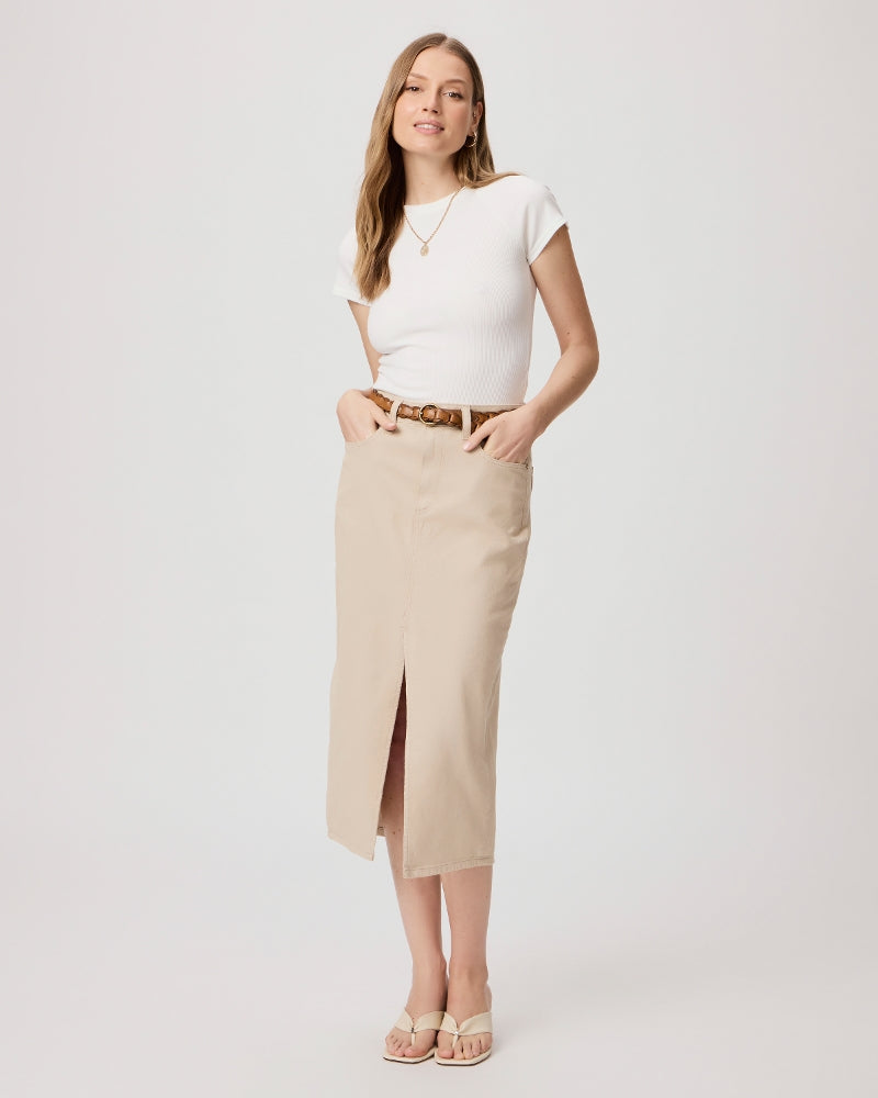 A woman in a white top and beige Paige Vintage Angela Midi Skirt - Soft Beige with a high waist, standing against a light background.
