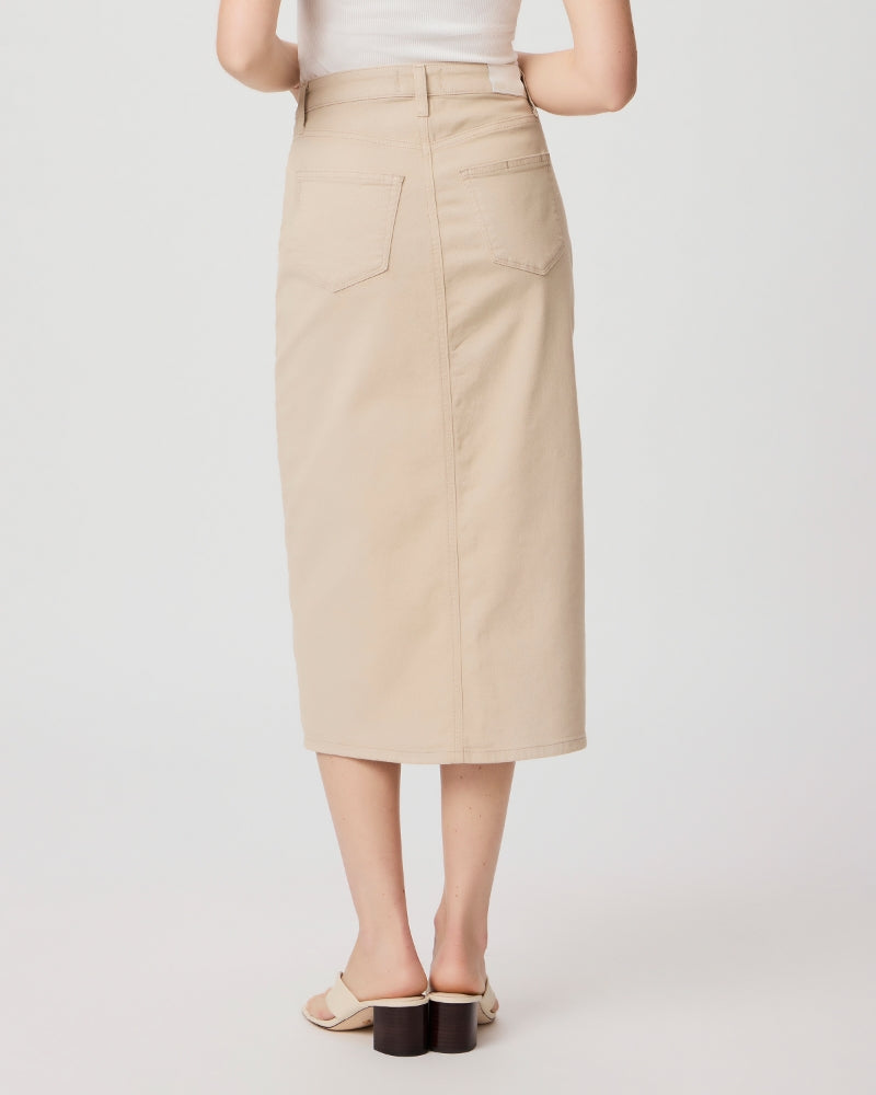 A woman wearing a Paige Angela Midi Skirt in Soft Beige and white sandals, viewed from the waist down against a light background.