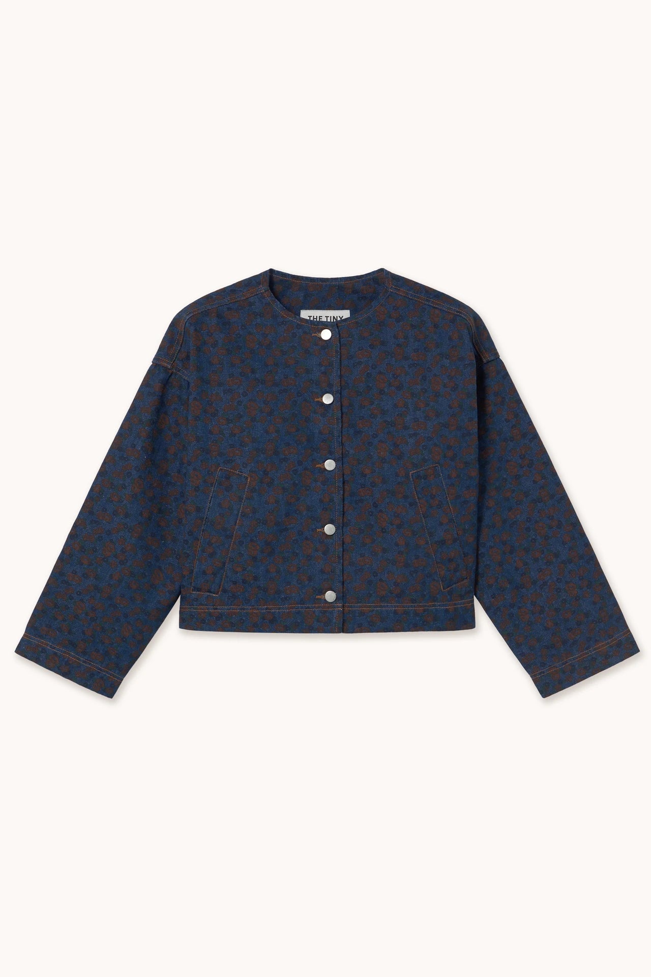 The Tiny Big Sister Flowers Cropped Jacket - Navy is an oversized, cropped denim jacket with long sleeves, a blue and brown floral print, button-up front, and front pockets, shown against a plain background.