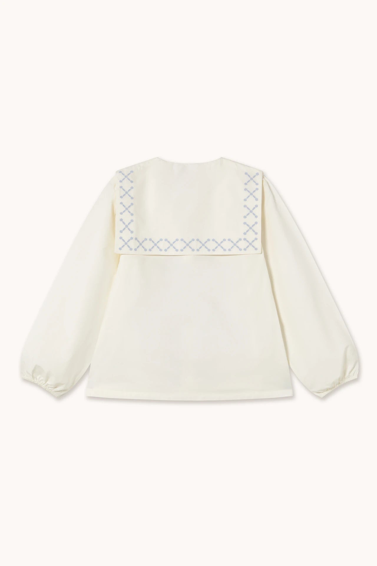 The Flower Embroidered Shirt - Ivory by Tiny Big Sister is a long-sleeve cotton blouse with a square sailor collar and blue cross-stitch embroidery—a timeless, sustainable fashion piece.