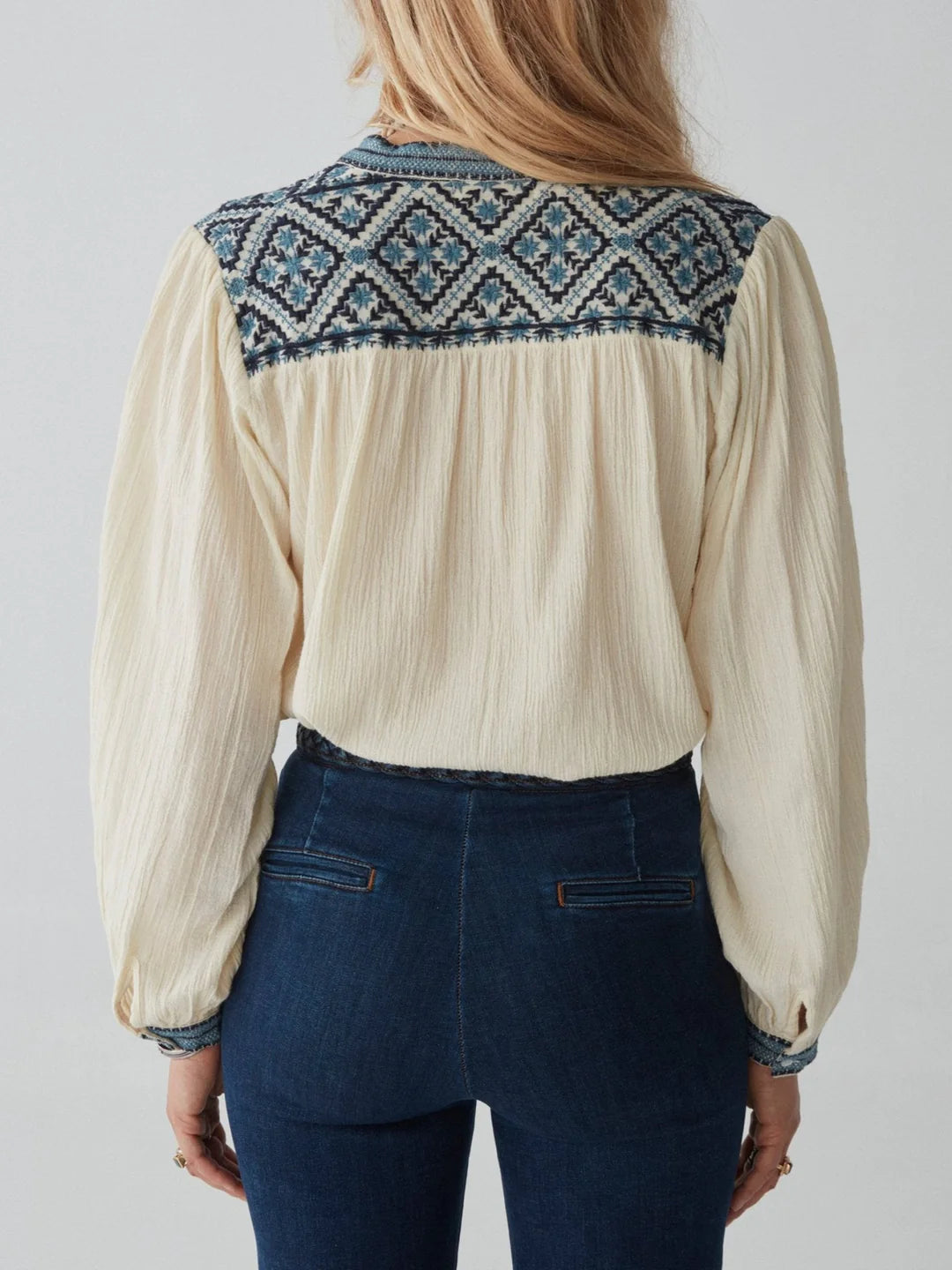 model wears cream blouse with embroidery and jeans