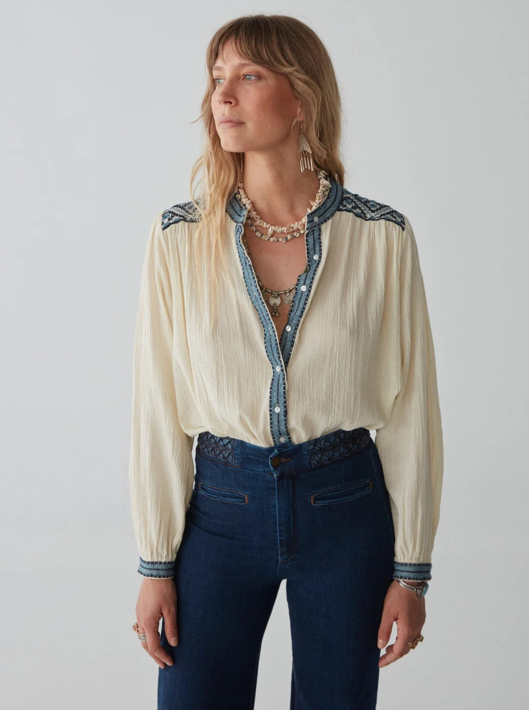 model wears cream blouse with embroidery and jeans