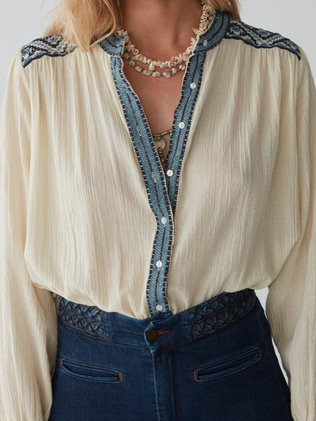 model wears cream blouse with embroidery and jeans