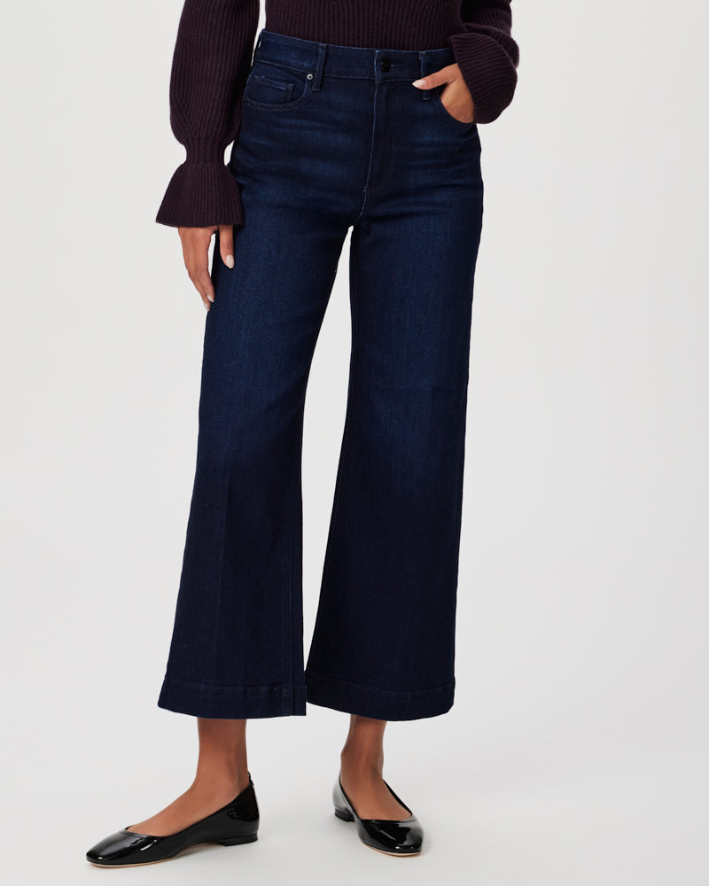 A woman is wearing a pair of Paige Anessa Wide Leg - Sussex denim cropped jeans and a sweater.