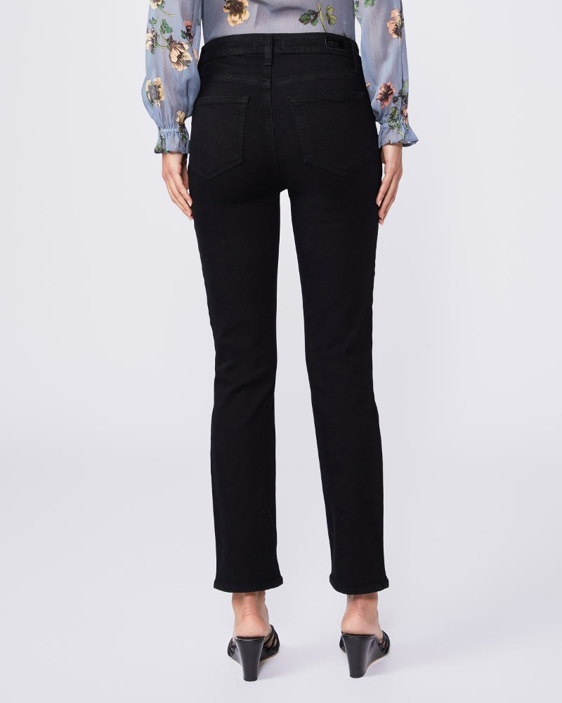 The back view of a woman wearing Paige Cindy Straight Ankle - Black Shadow jeans with a straight cut and a floral blouse.
