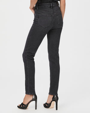 Model wears slim fitting straight leg jeans in a black wash colour. Back view.