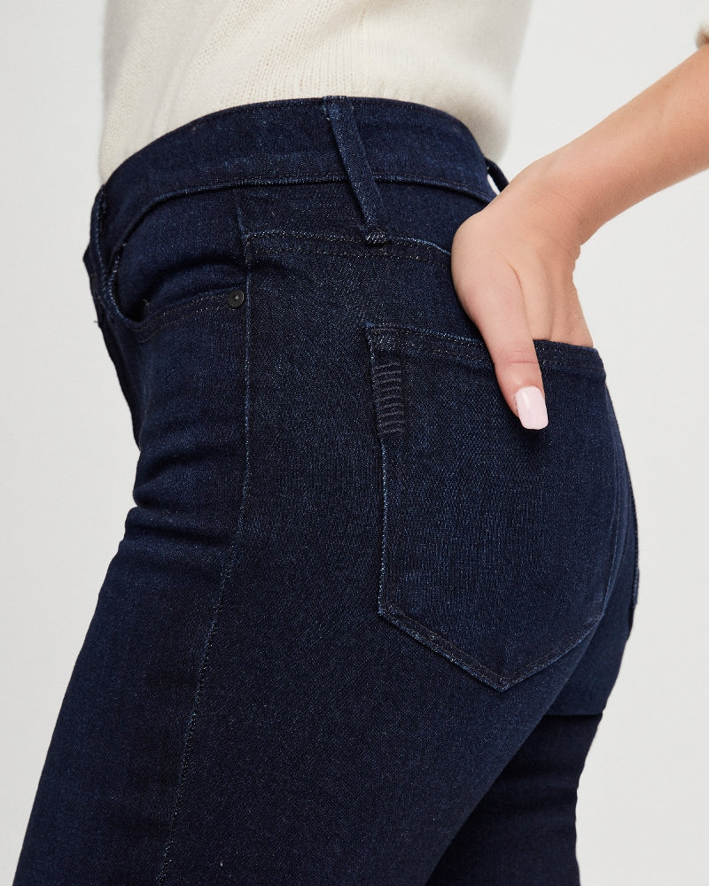 close up view of model wearing slim leg dark blue paige jeans with hand in back pocket