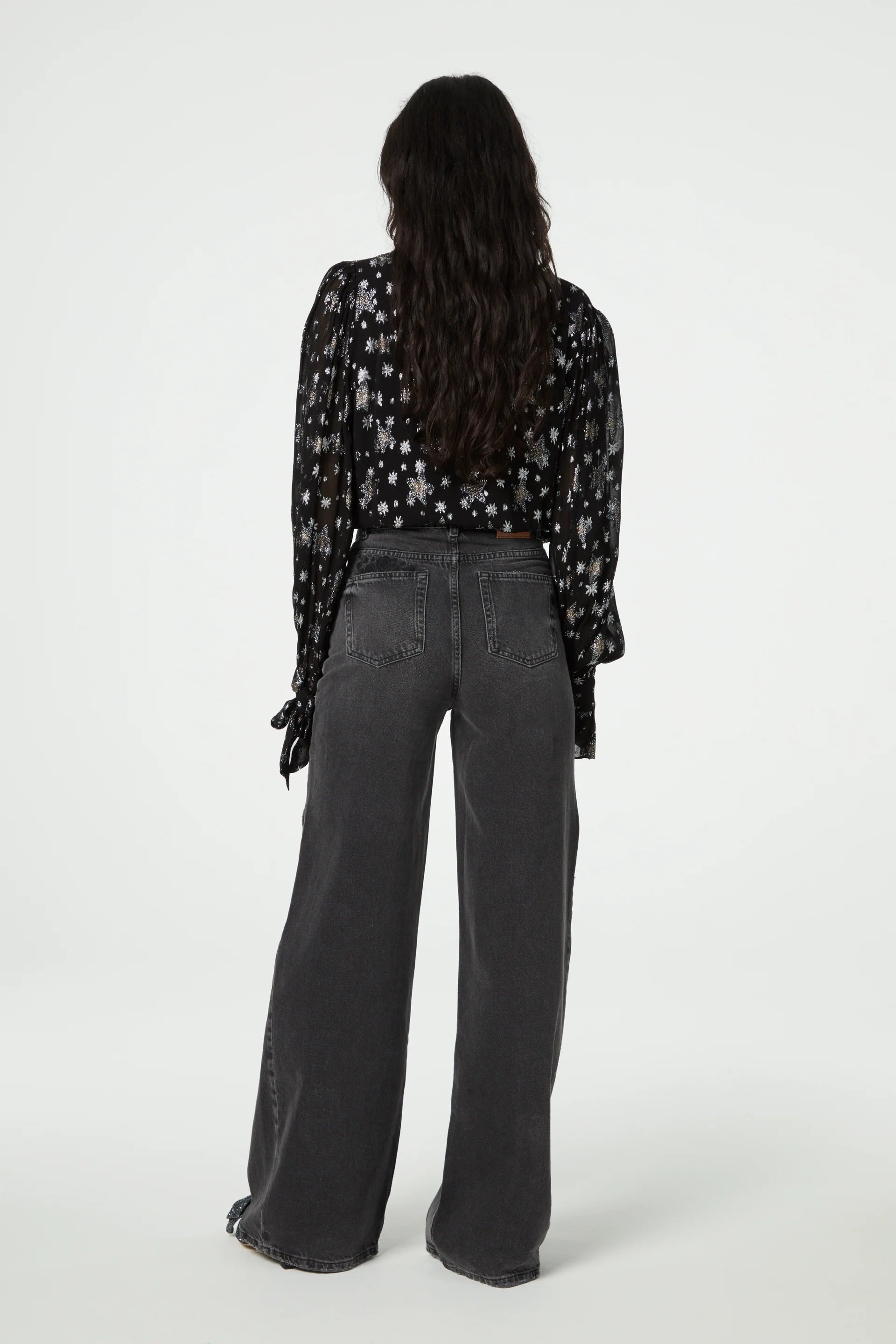 The back view of a woman wearing wide leg pants and a Fabienne Chapot Kylie Blouse - Starfleet with long sleeves.