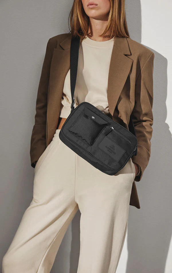 Woman in beige outfit with brown blazer carrying a black Markberg Darla Bum Bag made from vegan materials.