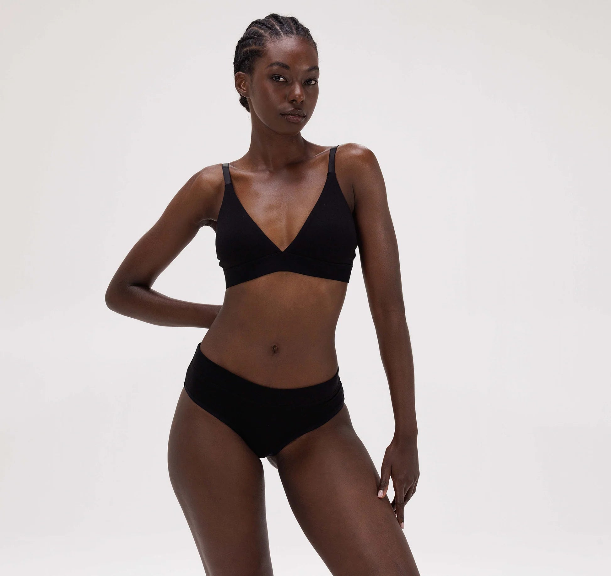 An Organic Basics Core Triangle Bra - Black providing support for a woman in a black bikini top and bottom.