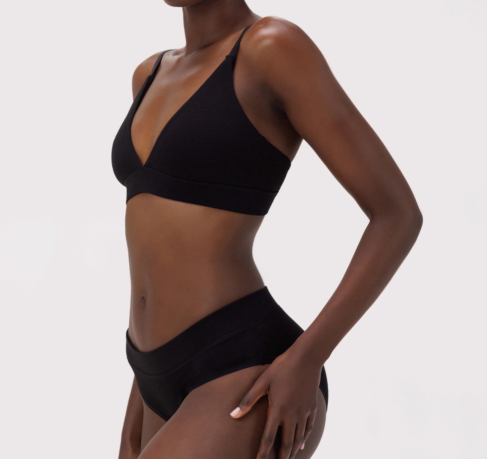 The model is wearing a black Core Triangle Bra by Organic Basics.