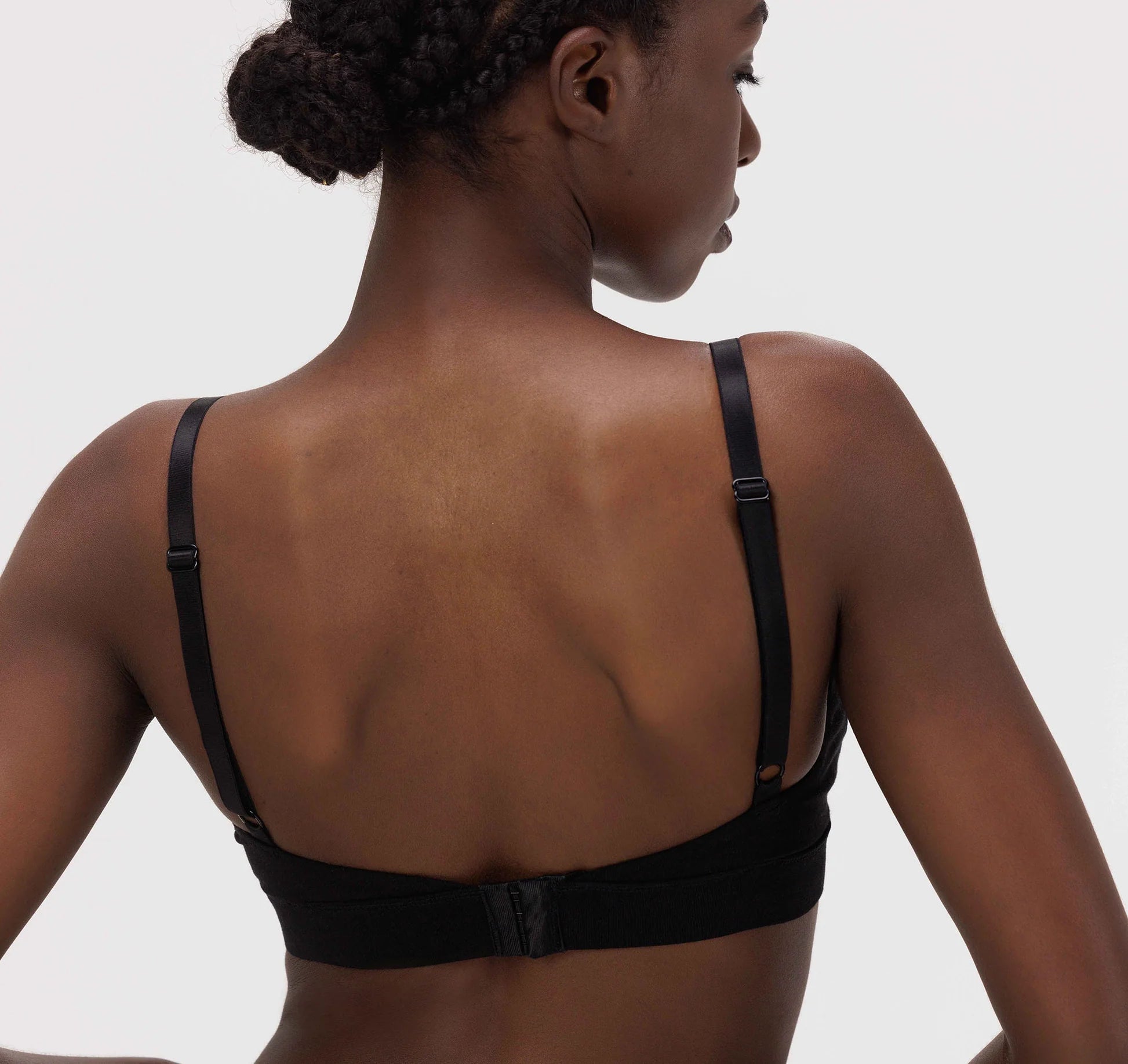 The back view of a woman wearing an Organic Basics Core Triangle Bra - Black.