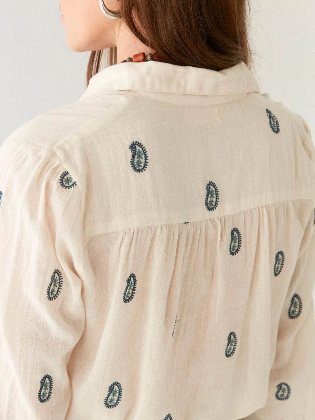 Close-up of a person wearing the Maison Hotel Dylan Blouse in ivory with small blue ovals, viewed from the back.