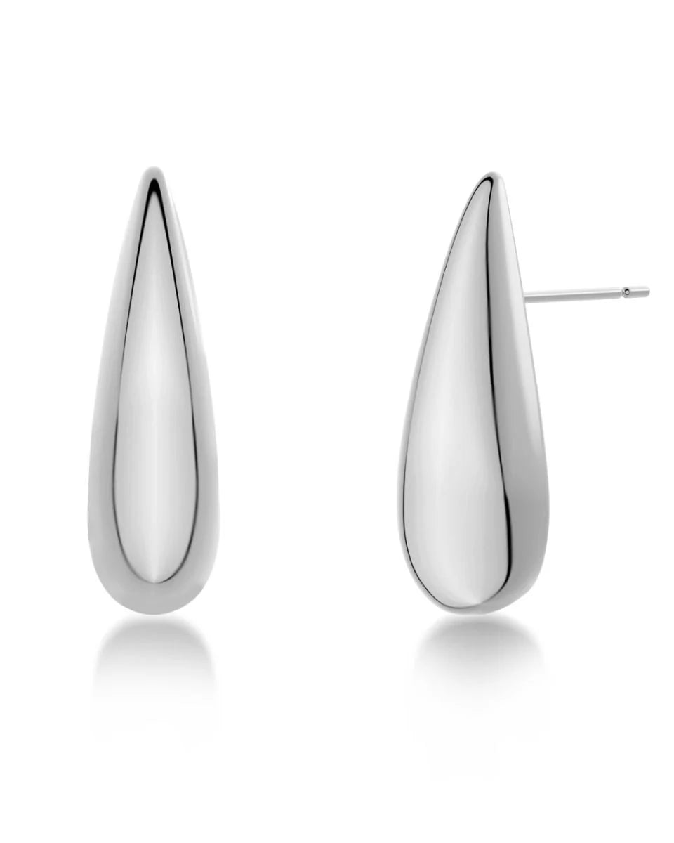 Introducing the Crest Studs by EDBLAD: a pair of sleek, teardrop-shaped white metal earrings with a smooth, reflective surface and post backings, featuring 14K gold plating.