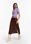 person wears a brown satin finish wrap style midi skirt by Essentiel Antwerp with a lilac top and cream pointy knee high boots