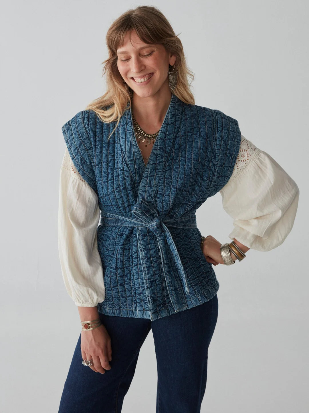 model wears quilted denim sleeveless jacket and white shirt and jeans