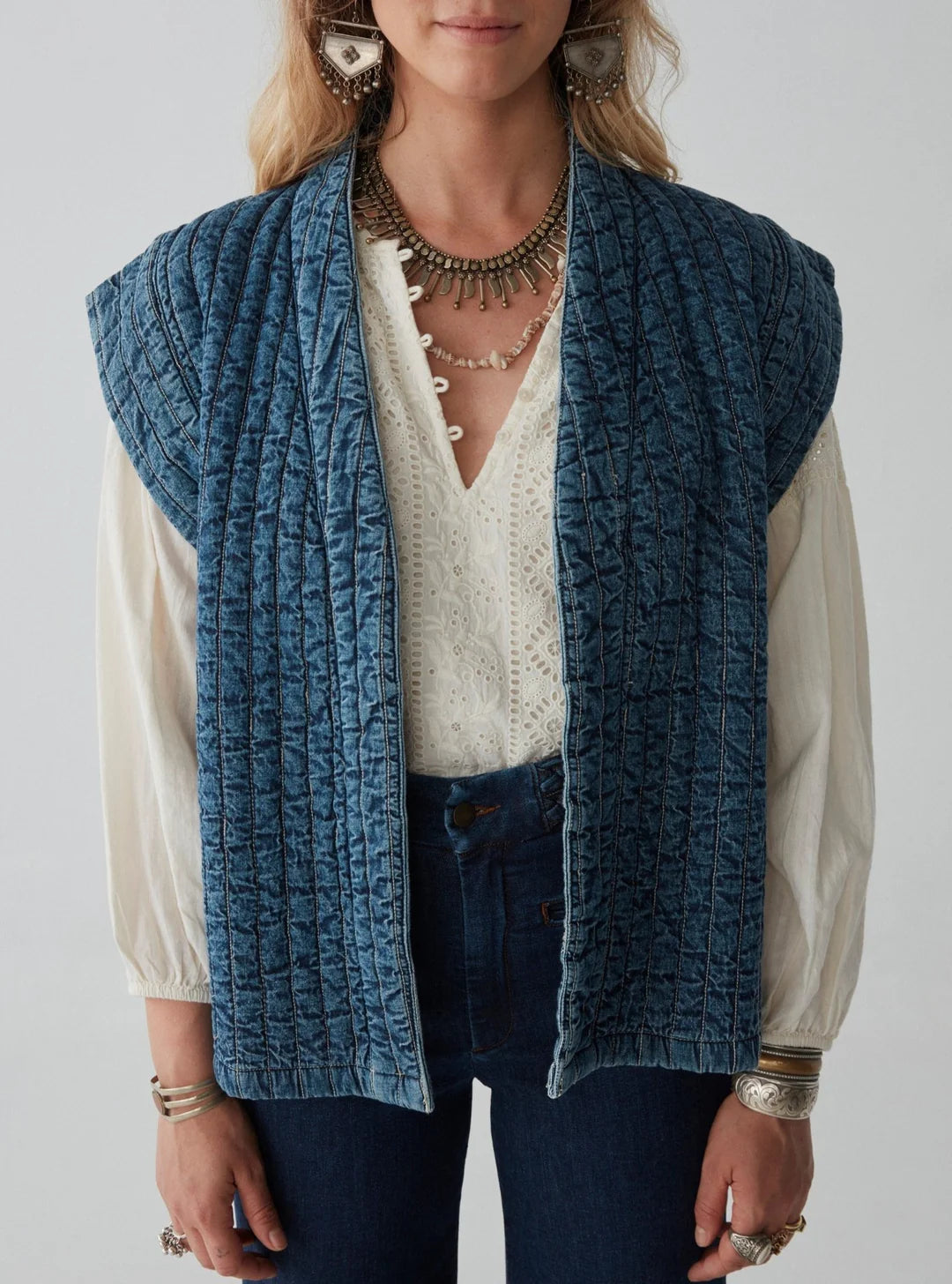 model wears quilted denim sleeveless jacket and white shirt and jeans