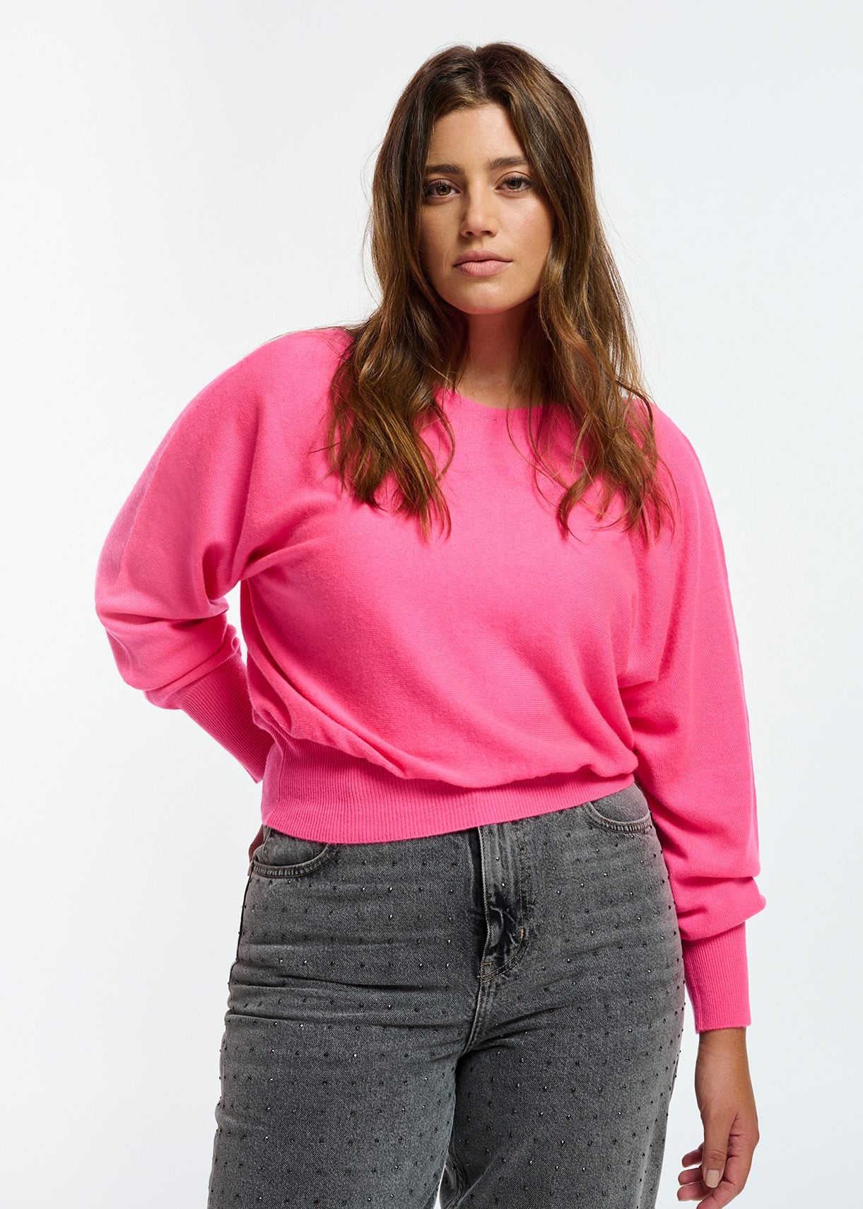 Model wears bright pink sweater with boat neckline.