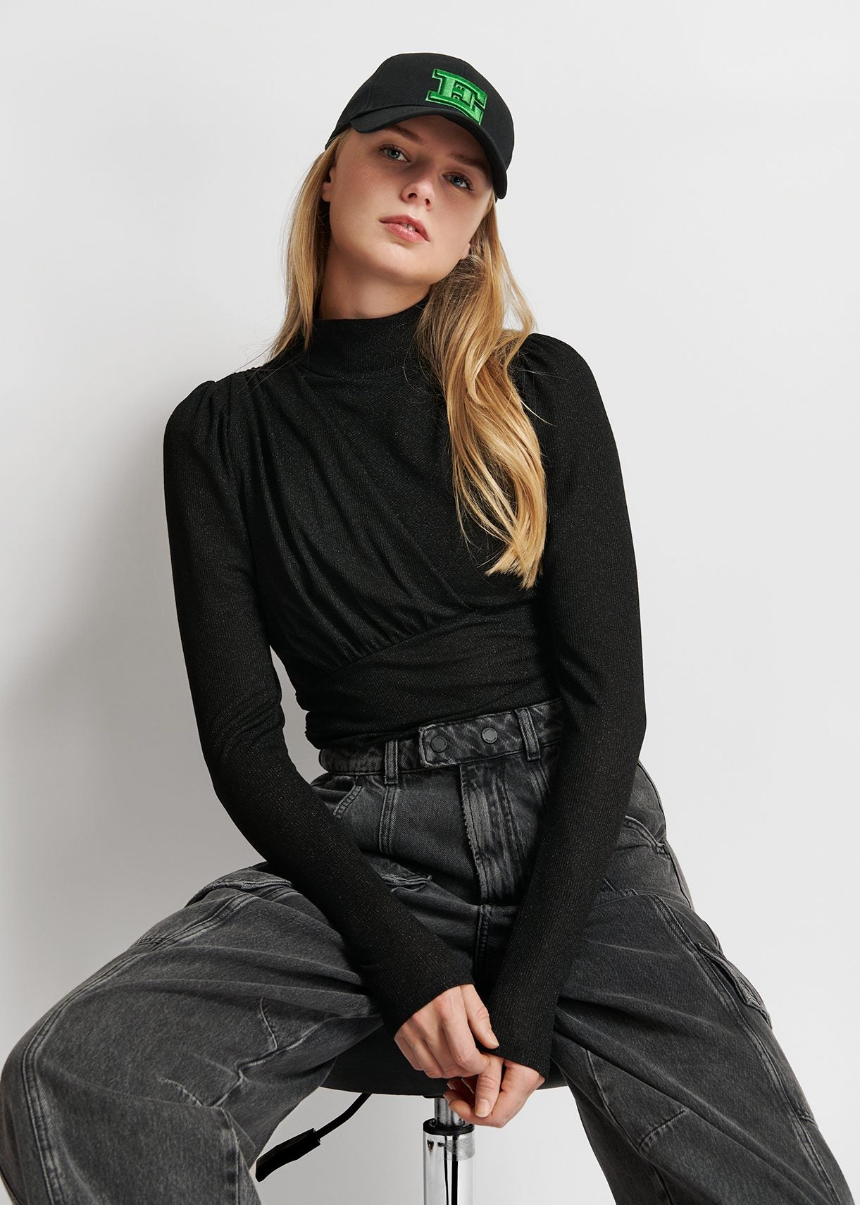 Model wears black long sleeve top with ruching on chest.