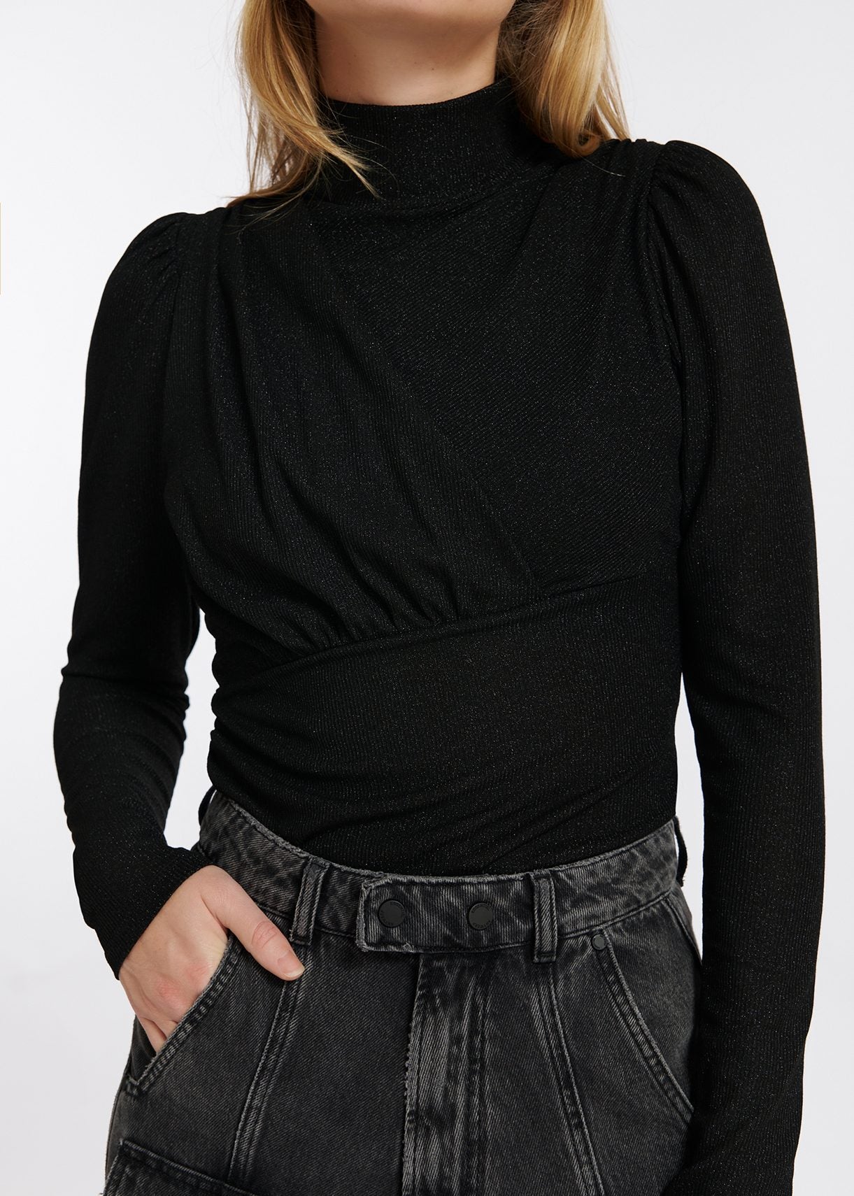 Model wears black long sleeve top with ruching on chest.