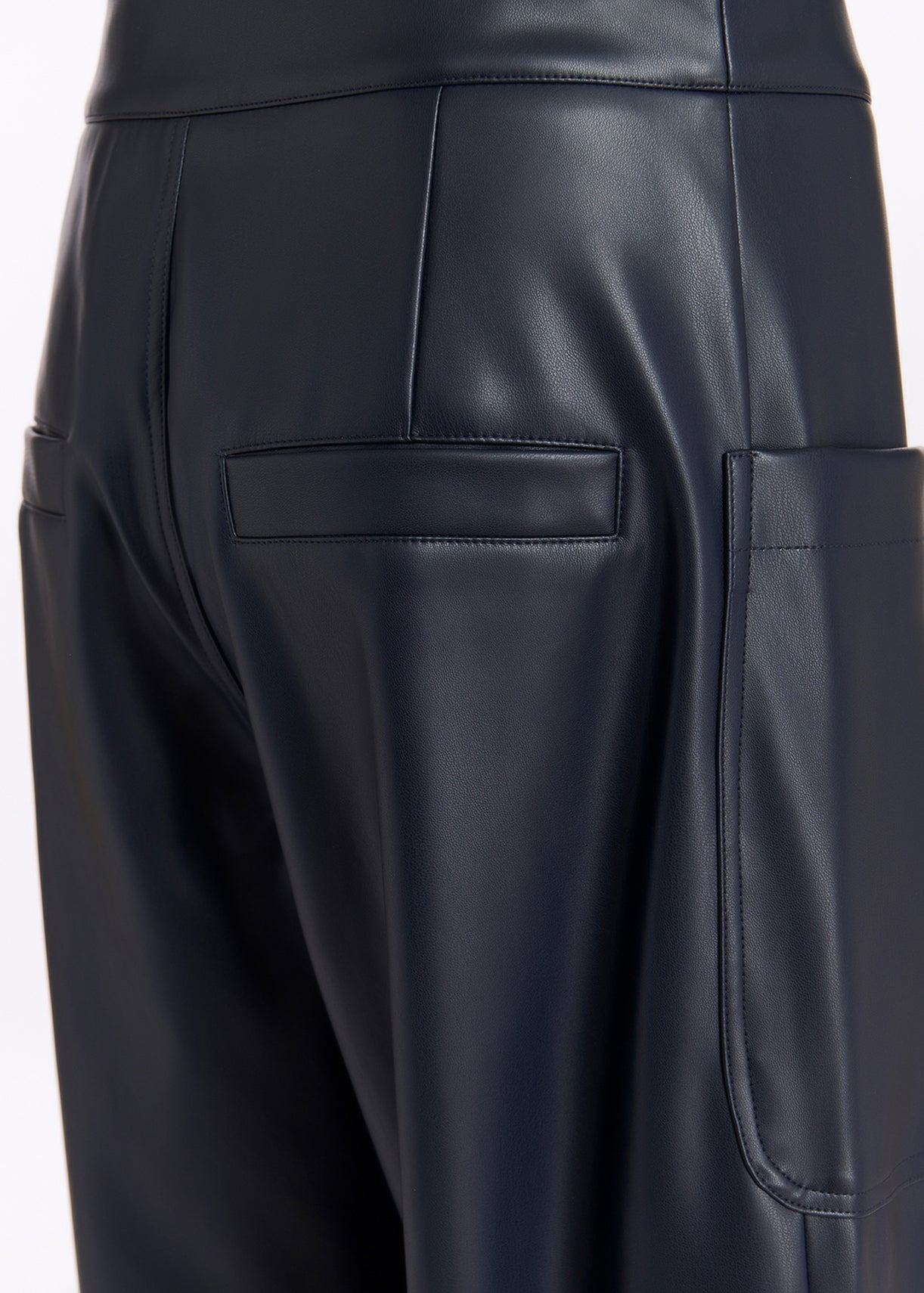 Close-up view of the back of a person wearing Essentiel Antwerp Grate Faux Leather Trousers in Navy, showcasing the back pockets and stitching details.