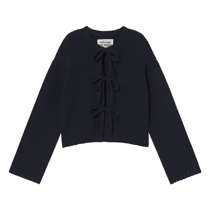 The Tiny Big Sister Tie Detail Cardigan - Navy is a long-sleeve, cropped knit with three front bow ties and a round neckline, shown on a white background.