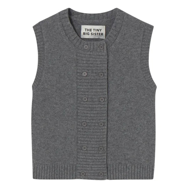 A dark grey, sleeveless knitted vest by Tiny Big Sister featuring a ribbed button placket, hem, and an inner collar label with the brand name.
