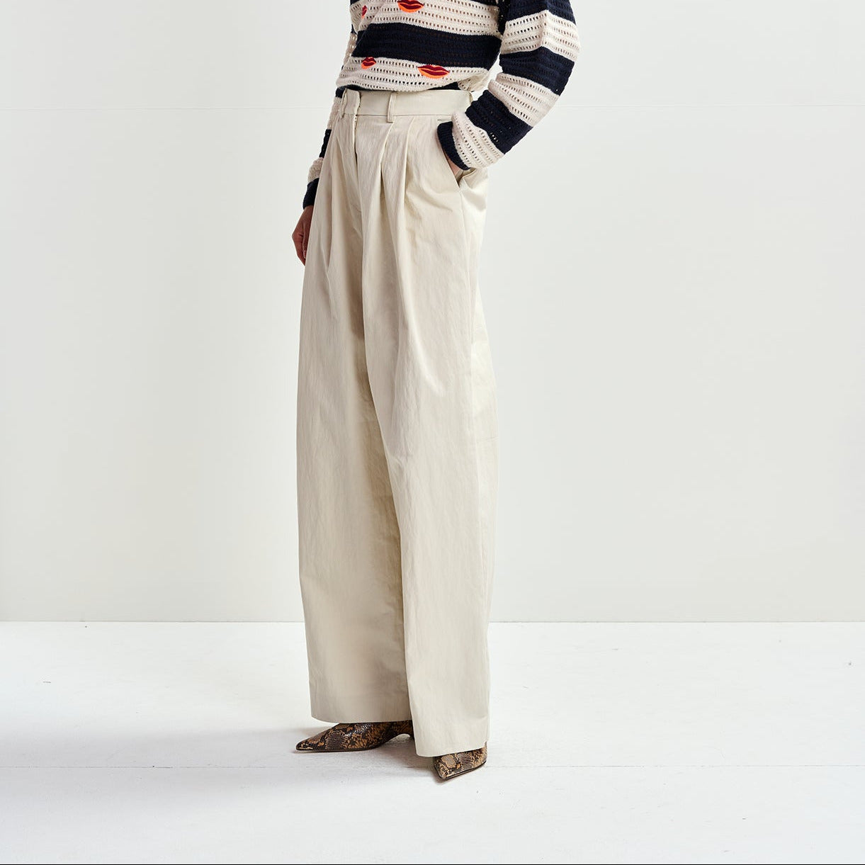 model wears white trousers and a stripe knit by essentiel antwerp