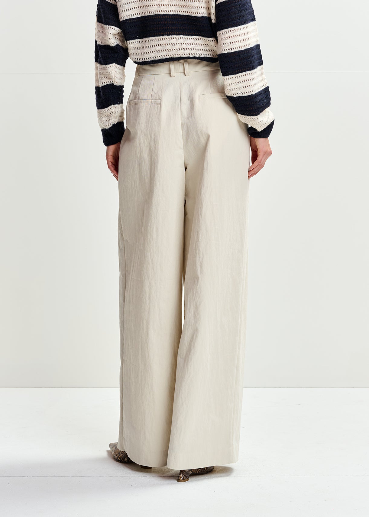 Person wearing a striped sweater and wide-leg pants on a white background
