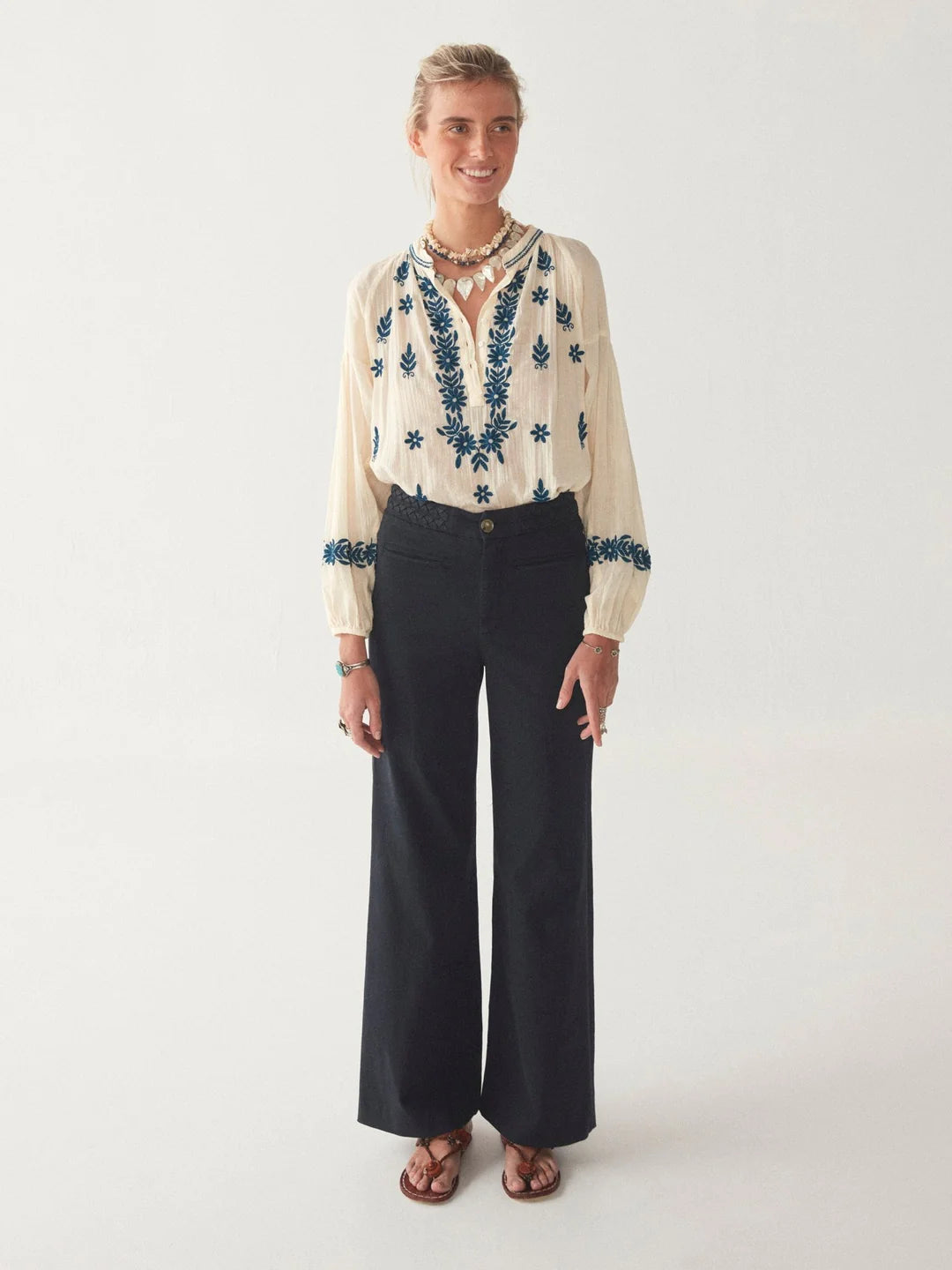 Model wears cream boho blouse with blue floral pattern on the front and cuffs
