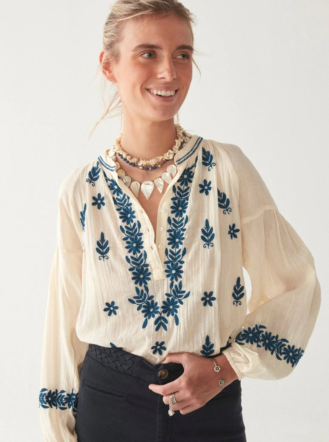 Model wears cream boho blouse with blue floral pattern on the front and cuffs