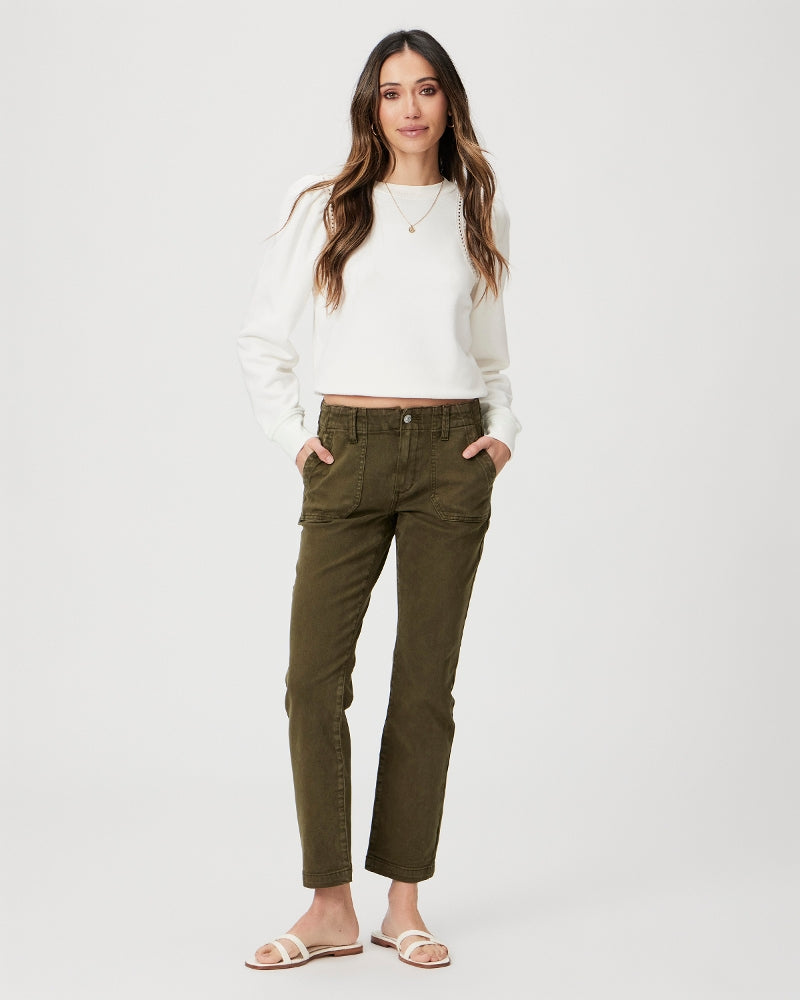 Woman wearing a white top and olive green mid-rise Paige Mayslie Straight Ankle - Vintage Olive Meadow jeans standing against a plain background.