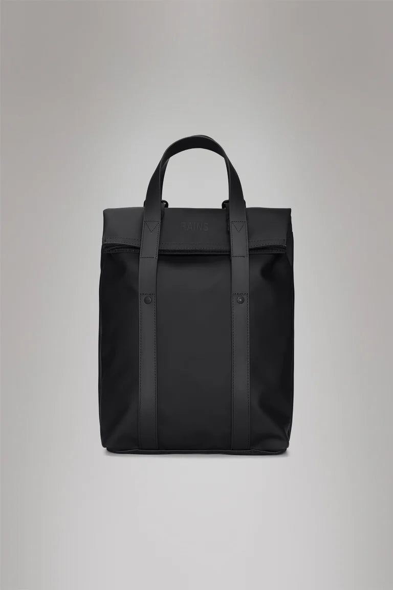 The Rains 2 Way Tote Backpack Mini is a black, rectangular bag with two top handles and a minimal design, ideal for commuters. Shown against a plain grey background.