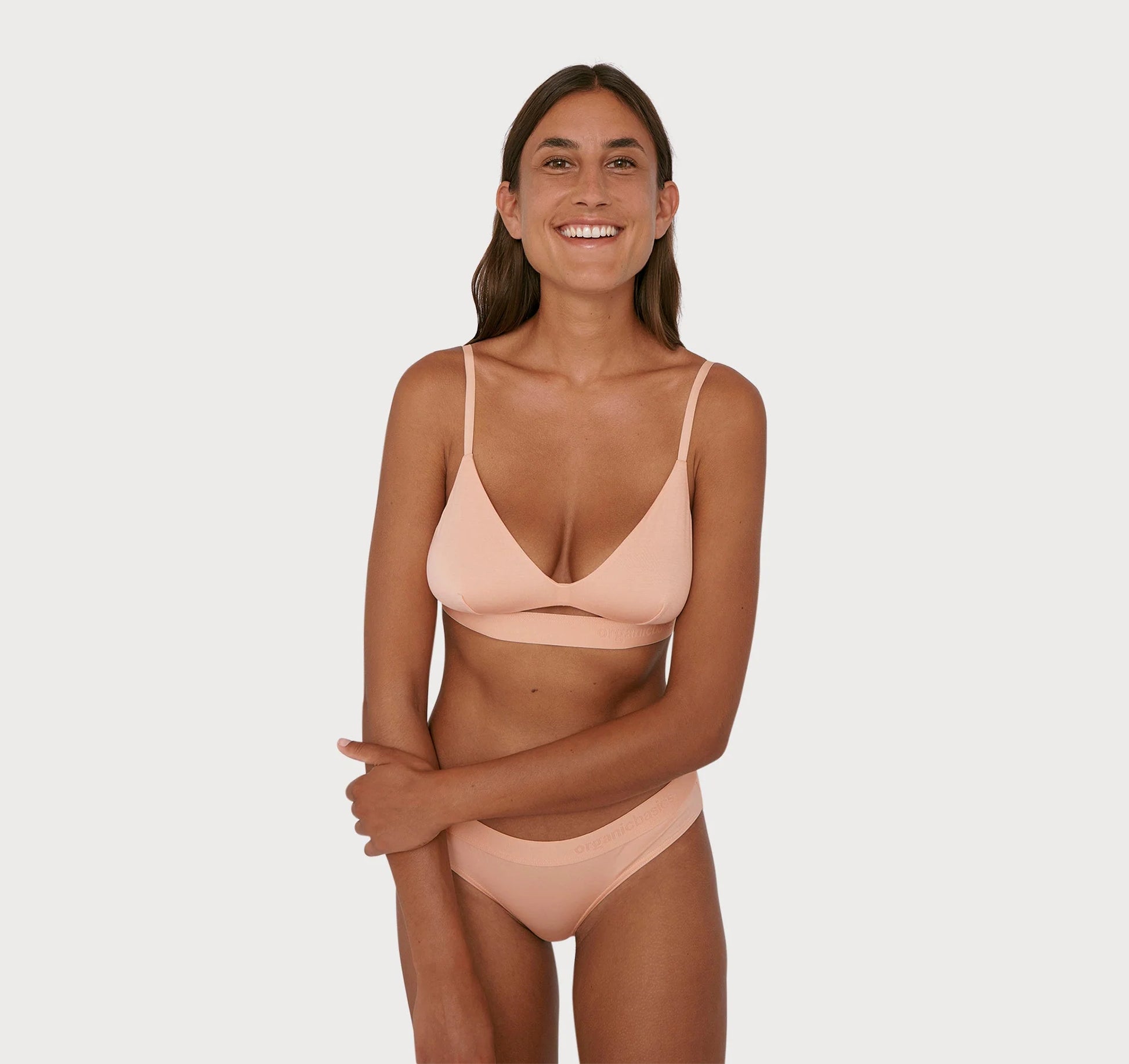 A woman in an adjustable Soft Touch Bralette - Soft Pink bikini by Organic Basics.