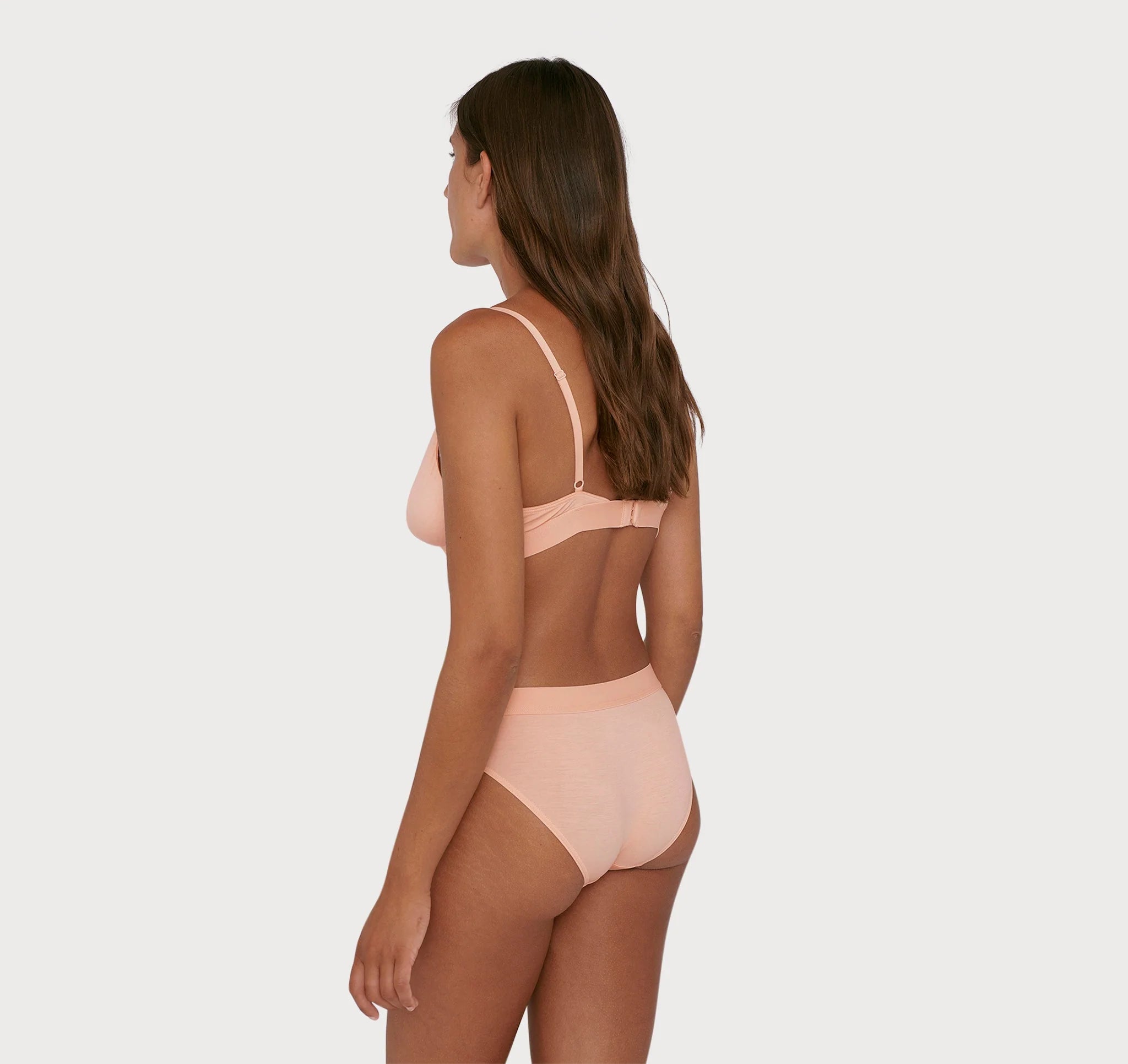 The back view of a woman in a comfortable Soft Touch Bralette - Soft Pink bikini by Organic Basics.