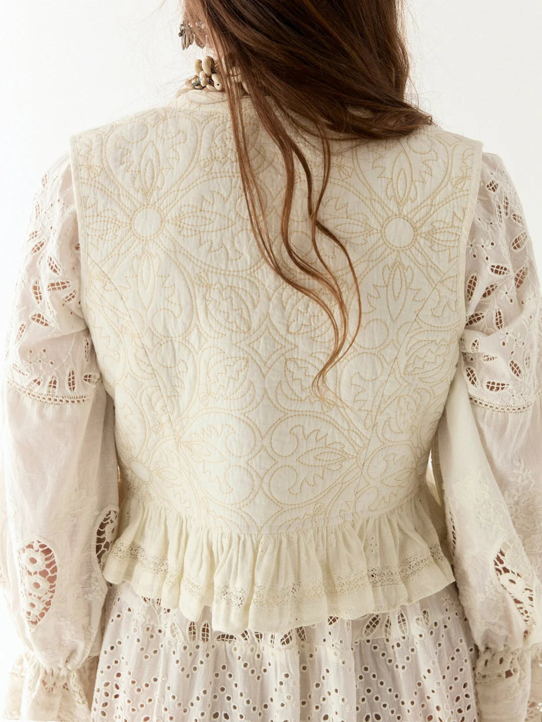 A woman is shown from behind wearing the Tesela Ivory Sandro Vest by Maison Hotel, highlighting its intricate back patterns.